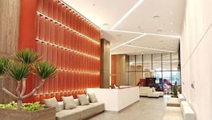 Eine moderne Lobby mit einer Rezeption, einer Sitzecke und einem großen Fenster.