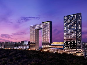 Et moderne hotel med en markant buet konstruktion, flere etager og oplyst skiltning.