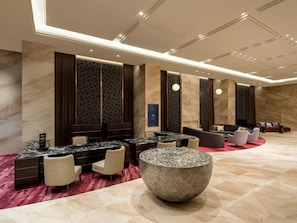 En moderne lobby med marmorbelægning, et receptionsskrank, siddeområde og dekorative vægpaneler.