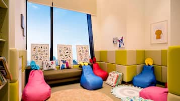 A children's playroom with a sofa, bean bags, a rug, and educational posters.
