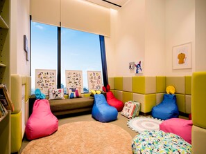 A children's playroom with a sofa, bean bags, a rug, and educational posters. - Grand Mercure Ambassador Seoul Yongsan (Seoul)
