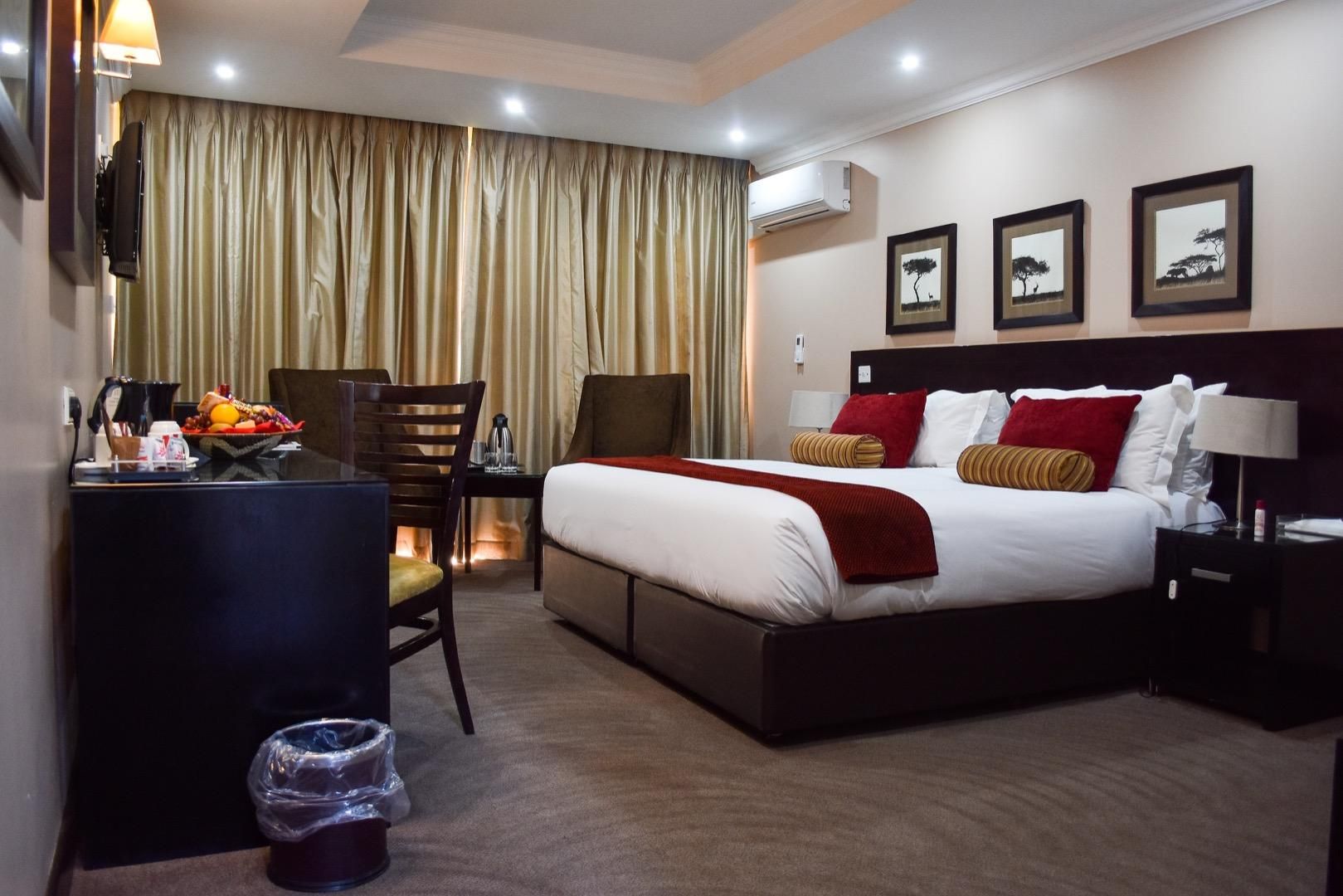 Una habitación de hotel con cama, mesita de noche, lámpara y escritorio con silla.