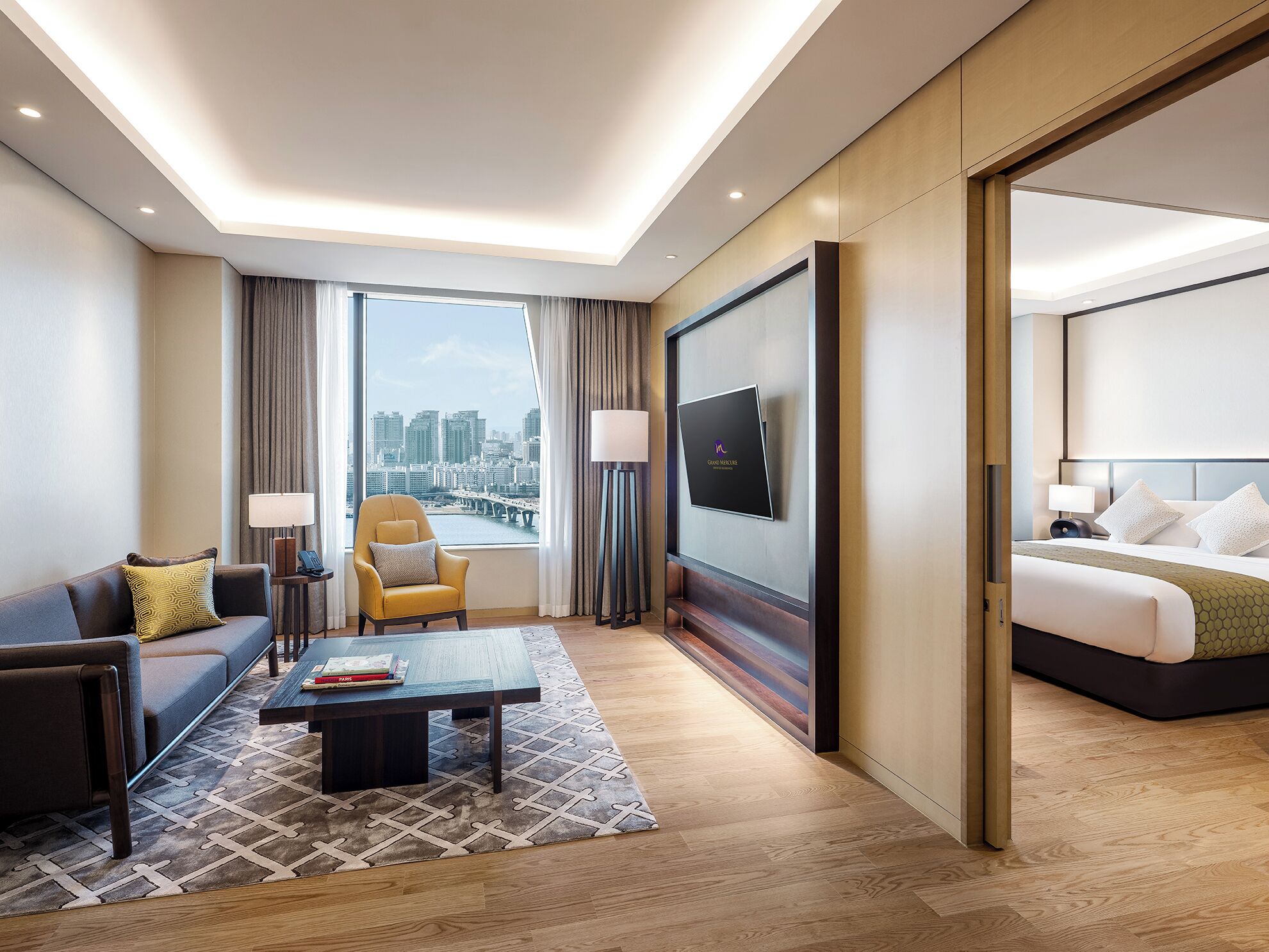 Une chambre d’hôtel équipée d’un canapé, d’un fauteuil, d’une table basse, d’une télévision et d’un lit.
