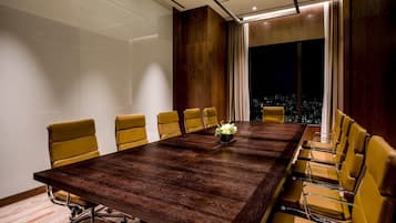 Une salle de conférence avec une longue table, des chaises jaunes et une vue sur la ville.