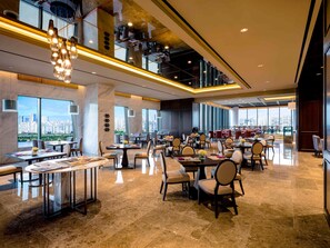 A spacious dining area with high ceilings, large windows offering city views, and modern lighting fixtures. - Grand Mercure Ambassador Seoul Yongsan (Seoul)