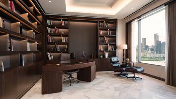 A modern office with a large desk, two chairs, and extensive bookshelves.