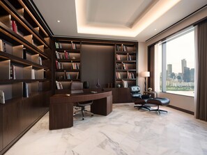 A modern office with a large desk, two chairs, and extensive bookshelves.