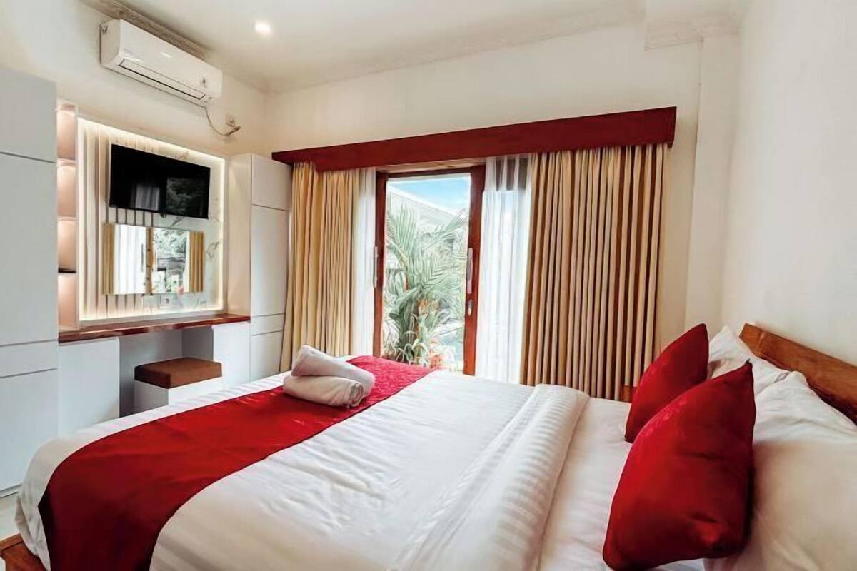 Een hotelkamer met een bed, een aan de muur bevestigde televisie en een raam met gordijnen.