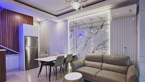 Una cocina moderna con refrigerador integrado, un comedor con mesa y sillas, y una sala de estar con sofá y una mesa de centro redonda.