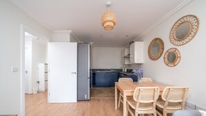 Et moderne køkken med hvide skabe, en blå bordplade og en hængende lampe.