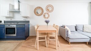Et moderne køkken med blå skabe, et træbord og en grå sofa.