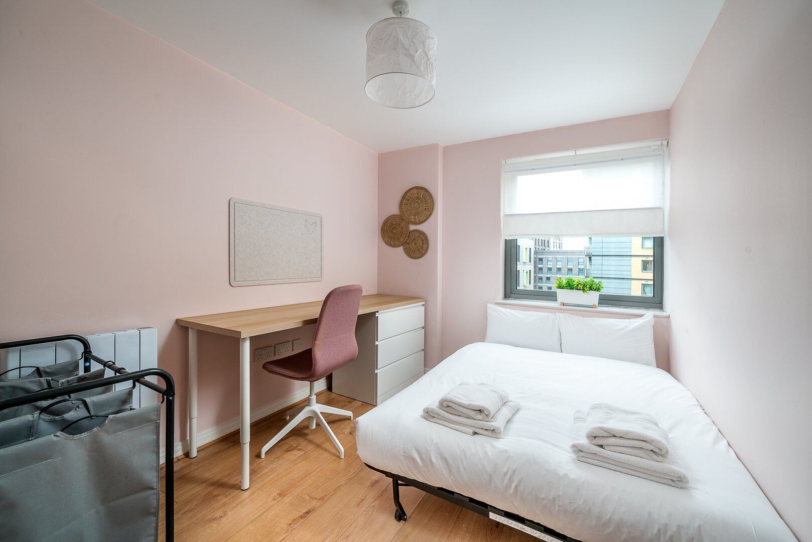 Una camera da letto con un letto, una scrivania, una sedia e una finestra vista edifici.