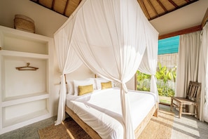 A bedroom with a four-poster canopy bed, a wooden nightstand, and a view of greenery outside. - Casa Nyang Uluwatu (Pecatu)