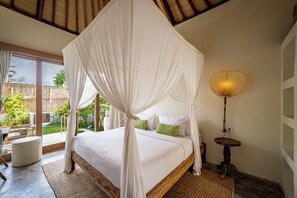 A bedroom with a four-poster bed, a bedside lamp, and a view of the outdoors. - Casa Nyang Uluwatu (Pecatu)
