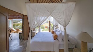 Quarto com cama de dossel, vista para a área externa e teto de madeira.