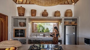 Uma cozinha moderna com ilha central, forno embutido, geladeira e cestos de vime nas prateleiras.