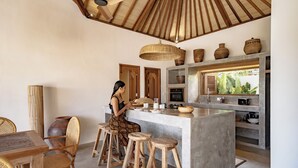 Uma cozinha com ilha central, banquetas de madeira e ventilador de teto.