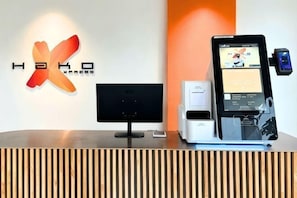 A reception desk with a monitor, a digital kiosk, and a logo on the wall. - Hako Xpress Tampoi (Johor Bahru)