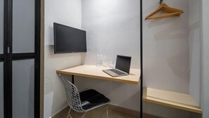 A small room with a desk, a chair, a television, and a coat rack. - Hako Xpress Tampoi (Johor Bahru)