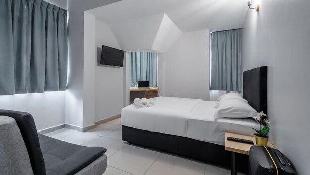 A modern hotel room with a bed, a desk, a chair, and a TV on the wall. - Hako Xpress Tampoi (Johor Bahru)