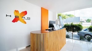 A modern reception desk with a logo, a large window, and a view of the street outside. - Hako Xpress Tampoi (Johor Bahru)