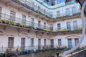 Un edificio de varios pisos con balcones, grandes ventanales y un patio central.