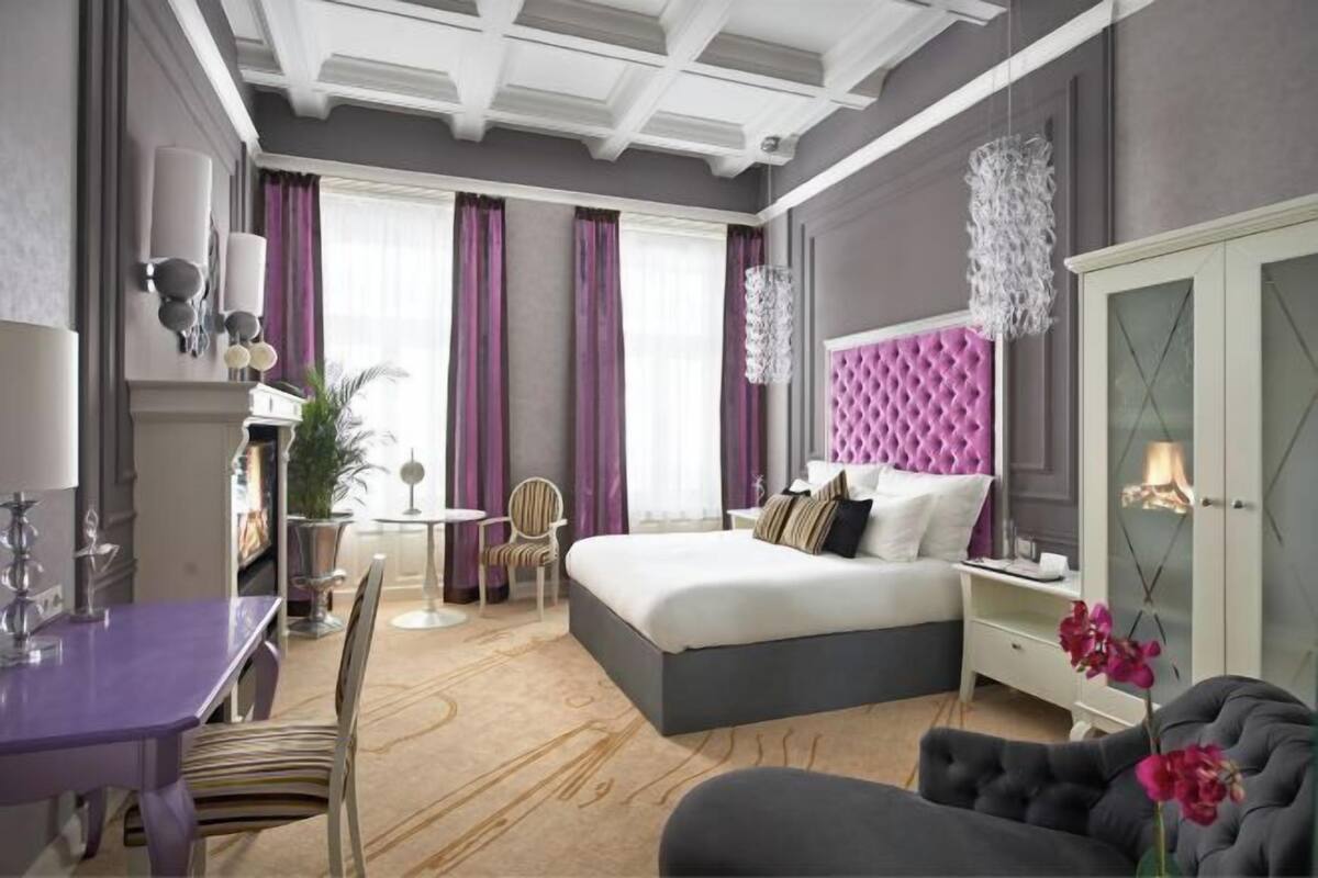 Ett modernt hotellrum med en stor säng, ett matbord och en sittgrupp.