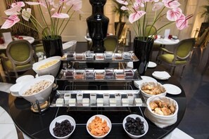 A buffet setup with various food items and a vase of flowers. - Aria Hotel Budapest by Library Hotel Collection (Budapest)