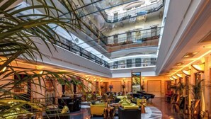 A multi-level atrium with a central seating area, glass railings, and a piano. - Aria Hotel Budapest by Library Hotel Collection (Budapest)