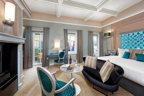 A hotel room with a bed, a sofa, a chair, a small table, and a fireplace. - Aria Hotel Budapest by Library Hotel Collection (Budapest)