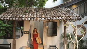 A woman in a red dress standing at the entrance of a building with a tiled roof and a sign that reads "Sera Suite." - Beldon Boutique Hotel (Dikwella)