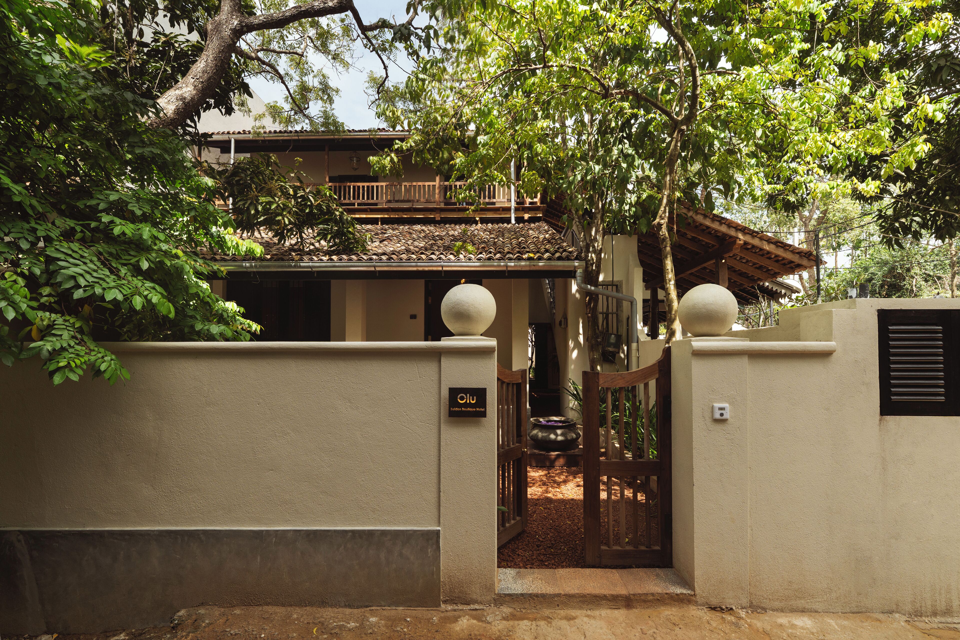 A traditional building with a tiled roof, a wooden balcony, and a gate with a spherical finial.