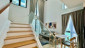 Una escalera que conduce a una sala de estar con sofá, mesa y sillas.