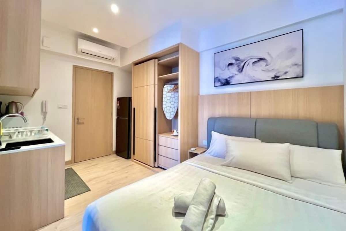 A hotel room with a bed, a wardrobe, a small desk, and a wall-mounted artwork.