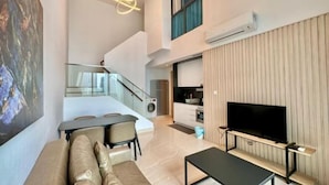 Una sala de estar moderna con un sofá, una mesa de centro, un televisor y una escalera que lleva a una cocina.