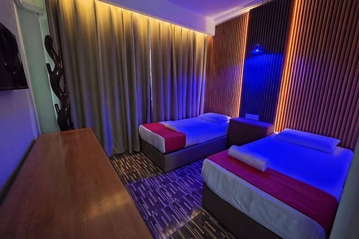 Ein Hotelzimmer mit zwei Betten, einem Holztisch und Vorhängen.