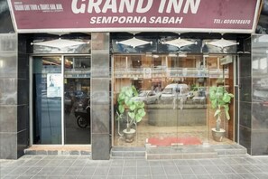 Een hotelingang met een bord waarop 'GRAND INN' en 'SEMPORA SABAH' staat.