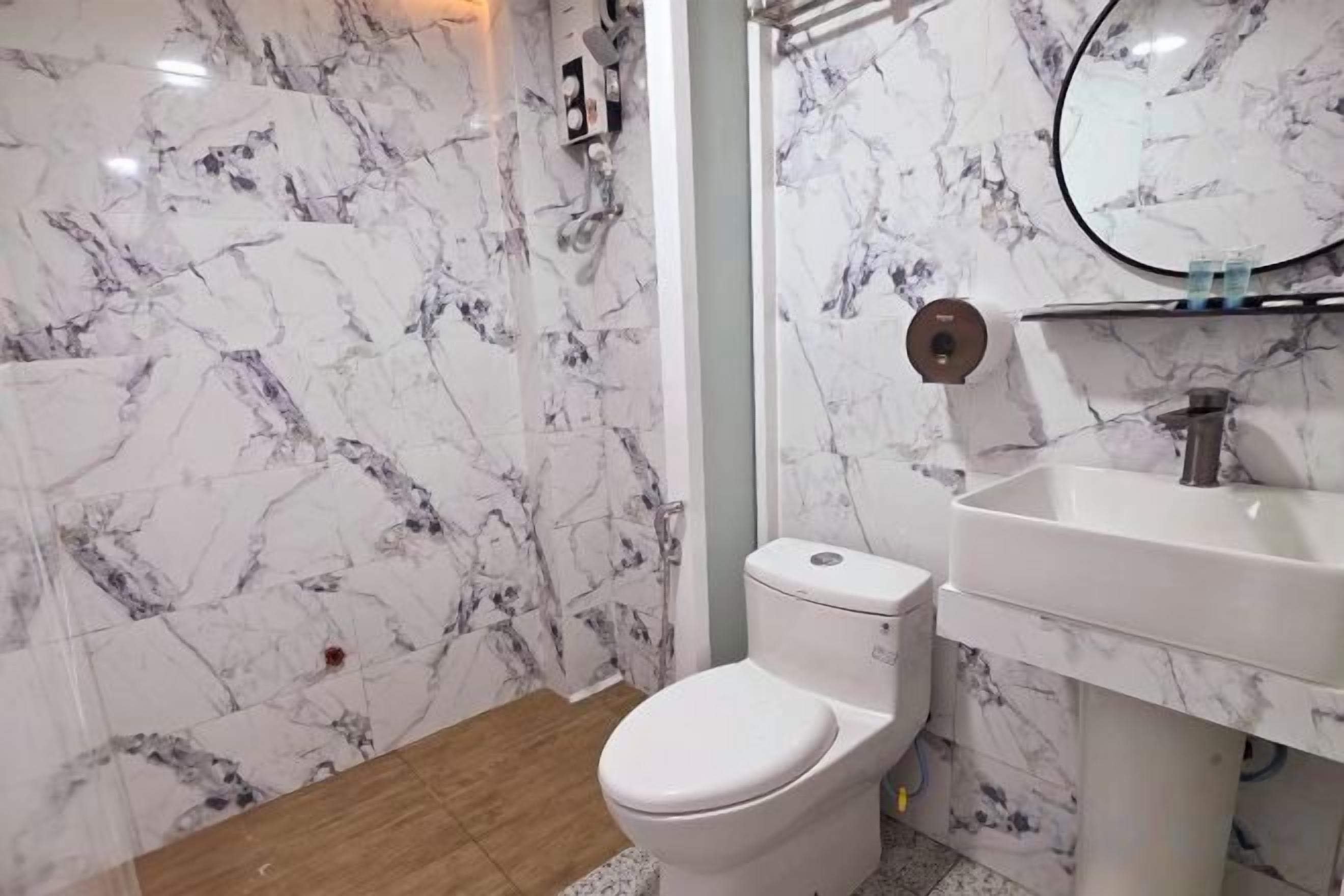 Une salle de bain avec des toilettes, un lavabo et des murs en marbre.