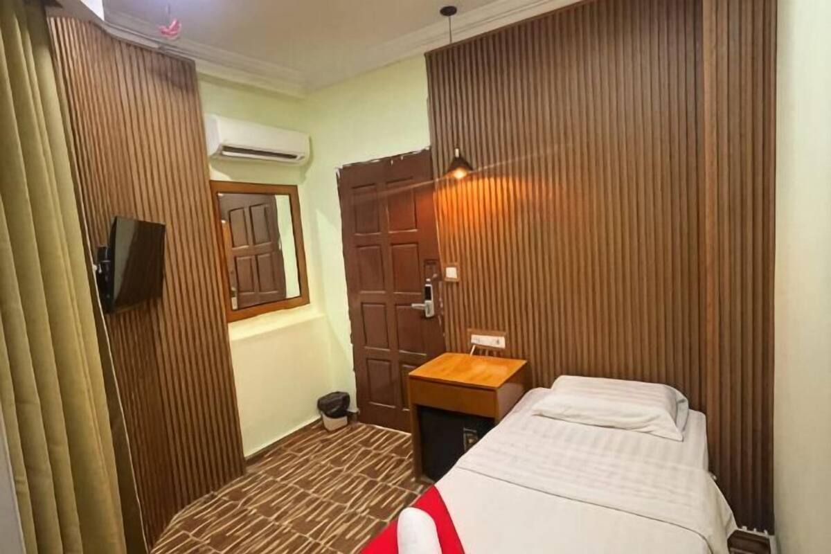Ein Hotelzimmer mit einem Bett, einem Holzschrank, einem kleinen Holztisch, einem Fernseher und einer Klimaanlage.