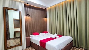 Una habitación de hotel con cama, espejo y cortinas.