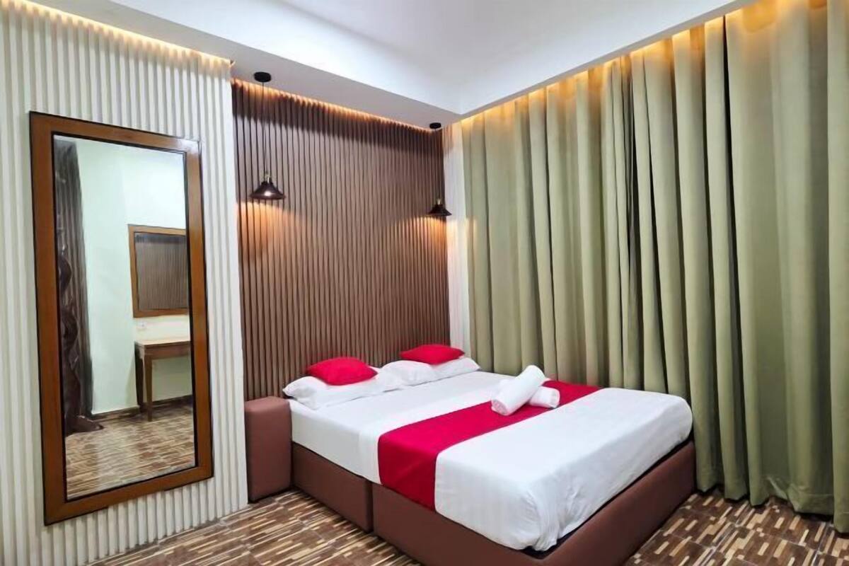 Ein Hotelzimmer mit einem Bett, einem Spiegel und Vorhängen.