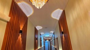 Un pasillo de hotel con paneles de madera, un candelabro e iluminación empotrada.
