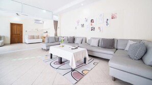 A modern living room with a grey sofa, a white coffee table, and a patterned rug. - Spacious 5-Bed Villa: 7 Mins to Walking Street (Pattaya City)