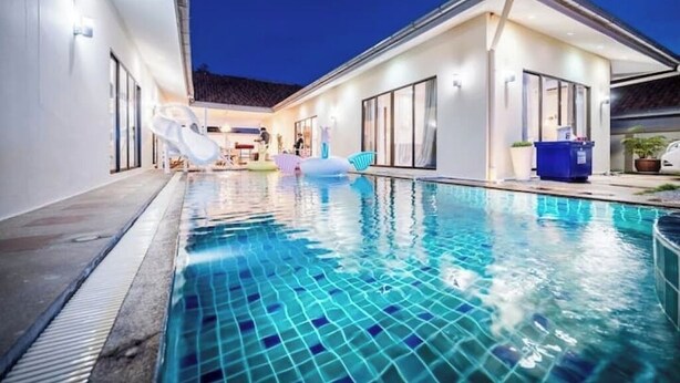 A modern house with a swimming pool, large windows, and a covered patio area. - Spacious 5-Bed Villa: 7 Mins to Walking Street (Pattaya City)