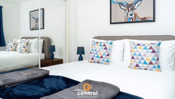 Ein modernes Hotelzimmer mit einem großen Bett, einem Spiegel und einem Bild von einem Reh.