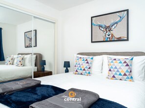 Una habitación de hotel moderna con una cama grande, un espejo y un cuadro de un ciervo.