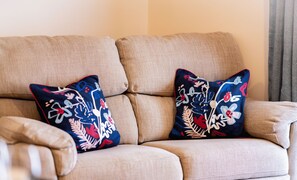 Een beige bank met kussens met een bloemenprint.