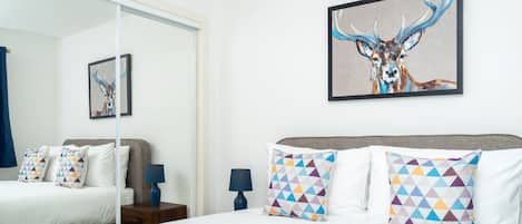 Una habitación de hotel moderna con una cama grande, un espejo y un cuadro de un ciervo.