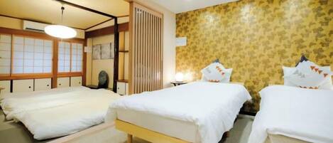 A hotel room with two beds, a traditional Japanese sliding door, and a patterned wallpaper.