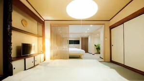 A hotel room with a large bed, a TV, a wardrobe, and a sliding door leading to another room. - Rakuyado Turuhashi (Osaka)